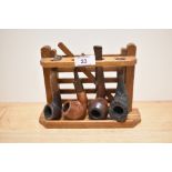 A vintage pipe rack in the form of a gate, sold with four pipes, including tug boat and Special R.