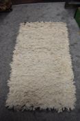 A 20th Century hand made long pile rug in cream