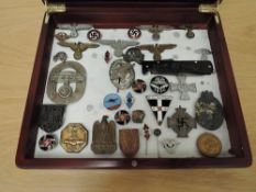 A display case containing 30+ German Badges, Cap Badges, Stick Pins, SS Pen Knife, nskk badge