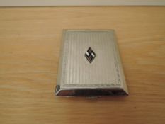 A German Third Reich silver plated Cigarette case, bearing enamelled Swastika badge, size 10.5cm x