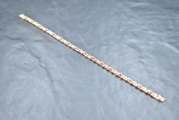 A 9ct gold articulated bracelet having ruby and diamond chip decoration with box clasp, approx 180mm