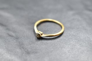 A diamond solitaire ring, approx 0.125ct in a collared mount on a yellow metal loop stamped 18ct/