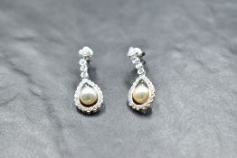 A pair of 18ct white gold diamond stud earrings having collared diamond drops to swing pearls in a