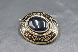 A Victorian gold and black enamel mourning brooch having a central bulls eye agate cabochon and