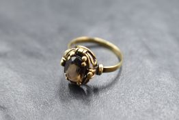 A smoky quartz ring having a decorative collared mount on a yellow metal loop, marks worn,