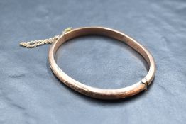 A 9ct rose gold hinged bangle having engraved decoration, approx 8.2g