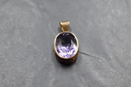 An oval amethyst pendant in a 9ct rose gold collared mount with moulded decoration, no chain, approx