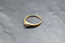 A diamond solitaire ring, approx 0.128ct in a claw set mount to split shoulders on an 18ct gold