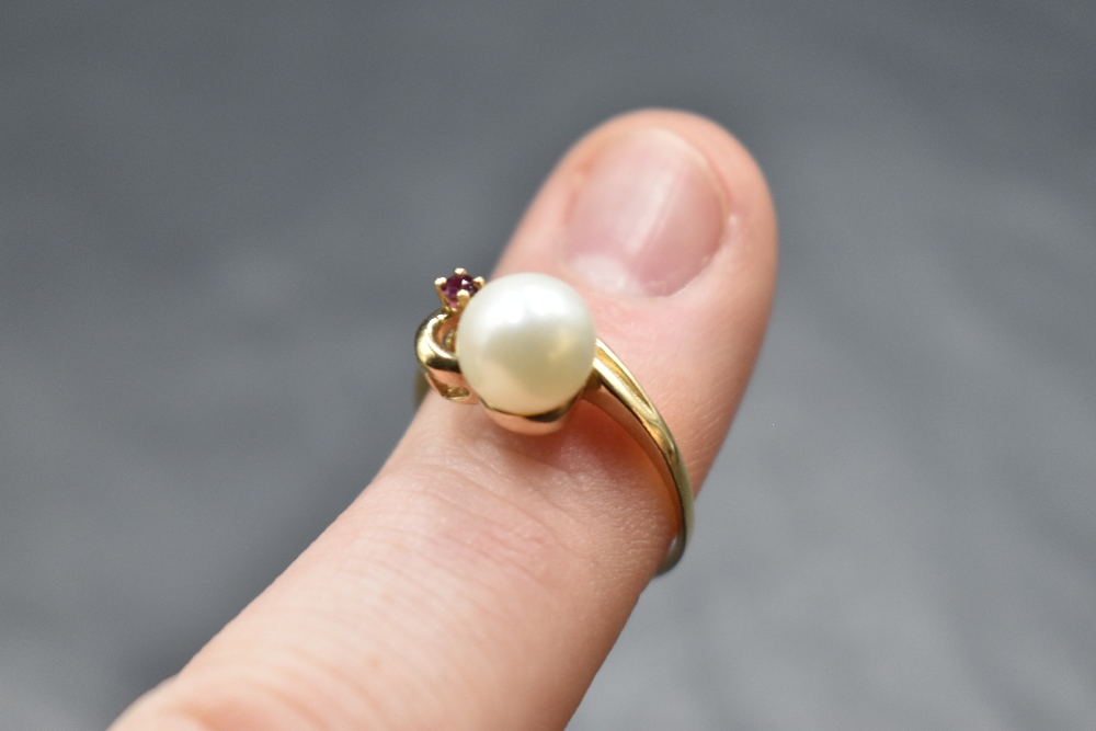A cultured pearl ring with ruby chip set swirl mount on a yellow metal loop stamped 10K, size N & - Image 2 of 2