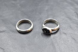 A pair of white metal Artisan made rings made to be worn together, one being a plain band, the other