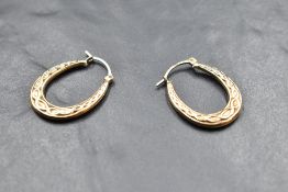 A pair of yellow metal hoop earrings for pierced earrings having moulded decoration, no marks,
