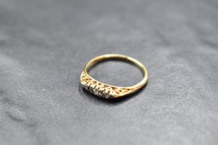 A dainty five stone graduated diamond ring in a boat shaped gallery mount on a yellow metal loop