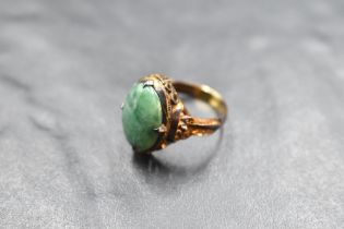 An oval jade cabochon ring in a four claw collared mount on a Chinese gold loop, size K and approx