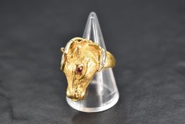A yellow metal ring stamped 750 in the form of a moulded horse's head having ruby and diamond chip