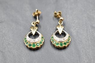 A pair of 9ct gold stud earrings having open circular drops with diamond and emerald chip
