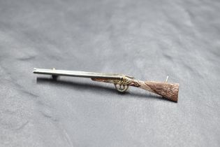 A 9ct tri coloured gold brooch in the form of a 12 bore shot gun having detailed decoration,