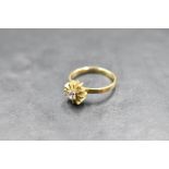 A diamond solitaire ring, approx 0.125ct in a 4 claw set stylised sun buerst mount on an 18ct gold