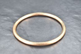 An Edwardian 9ct rose gold slave bangle of plain tubular form, inner diameter 70mm & approx 8.8g