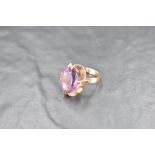 An oval amethyst ring having a claw set stylised mount on a 9ct gold loop, size M & approx 4.7g