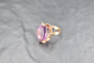 An oval amethyst ring having a claw set stylised mount on a 9ct gold loop, size M & approx 4.7g