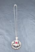 An Edwardian white metal hinged pendant having central cushion cut ruby within a diamond set mount