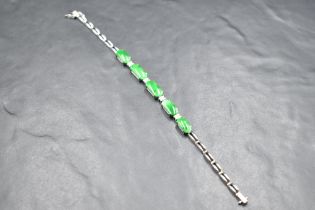 An 18ct white gold articulated bracelet having five oval jade style panels interspersed by four