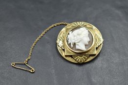 A conch shell cameo brooch depicting a Grecian maiden in profile in a three layer yellow metal