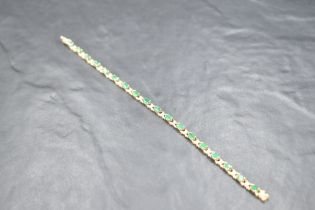 A 9ct gold articulated bracelet having oval emerald coloured stones interspersed by diamond chips,