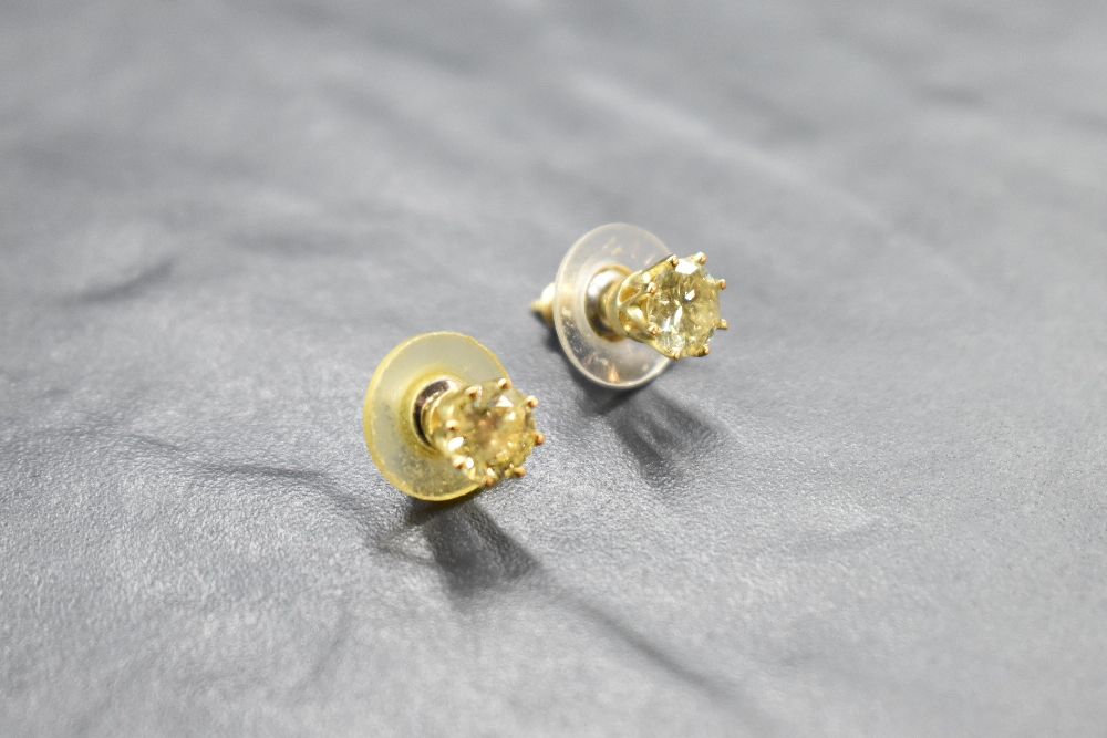 A pair of fancy pale yellow diamond solitaire earrings in yellow metal claw set mounts with ridged - Image 2 of 2