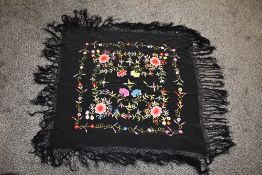 An early 20th century fringed shawl, having vibrant embroidery.