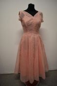 A beautifully tailored 1950s sheer flocked full skirted dress in pale pink with a matching pink