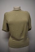 A 1950s sage green crepe blouse, having button back fastening, shoulder pads and white beading to