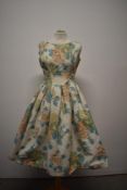 A 1950s cotton day dress, having abstract floral pattern, tie belt to waist and full pleated skirt