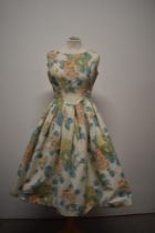 A 1950s cotton day dress, having abstract floral pattern, tie belt to waist and full pleated skirt