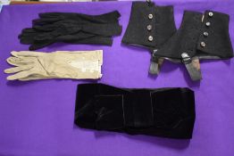 A pair of early 20th century black felt spats, two pairs of gloves and a black silk velvet belt.