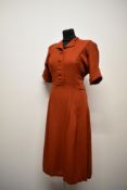 A 1940s rust coloured day dress, in a medium weight textured fabric, having self covered buttons