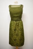 A 1950s evening dress of fitted form, in olive with gold floral patterned satin, having crepe