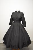 A black taffeta 1950s evening dress, having very full skirt with pleats, back metal zip and tie belt