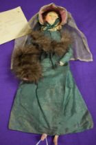 An unusual circa 1830s doll, having green silk draw string compartment to skirt to house