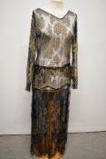 A sheer 1920s dress, having metallic gold thread work, long sleeves, v neckline, and tie fastening