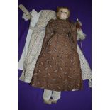 A circa 1820s doll, having plaster hand painted head with glass eyes, having original clothes and