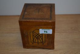 A novelty treen cigarette dispenser with marquetry inlay, measuring 11cm x 10cm x 10cm