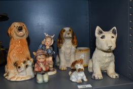 An assorted collection of ceramic and porcelain dog ornaments plus two Goebel Hummel figures