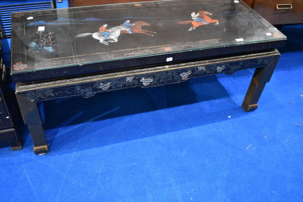 A Japanesque black laquered coffee table, with horse decoration