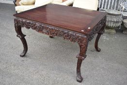 An Oriental hardwood dining table having heavily carved legs`