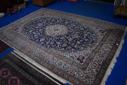 A traditional carpet square in shades of blue, cream and burgundy, holed towards one end, approx.