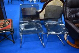 A pair of vintage chrome frame dining chairs with smokey perspex seats