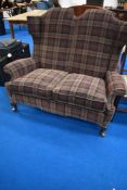 A Queen Anne Style wingback two seater settee with later tweed upholstery