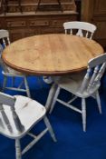 A pine and painted kitchen table, having circular top on scroll legs ad a set of 4 similar chairs