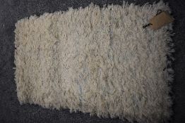 A 20th Century hand made long pile rug in cream